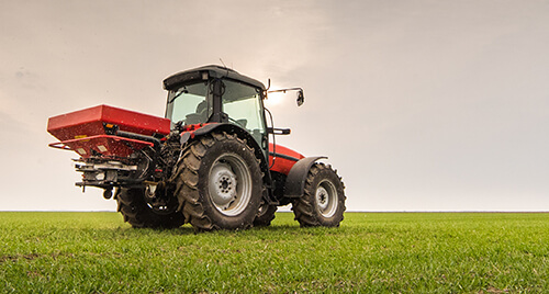 Farm Insurance: Large, red tractor with a sprayer parked in a field